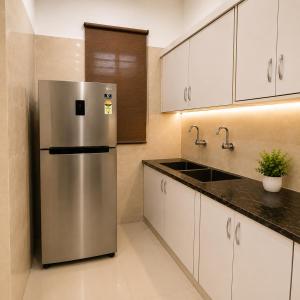 a stainless steel refrigerator in a kitchen with white cabinets at The Crown Resort in Sonīpat