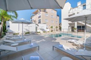 a pool with chairs and umbrellas and a building at Apartamento las palmeras 2 Planta 3 in Cala Millor