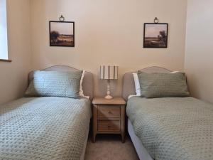 two twin beds in a room with a night stand at Thorn Tree Cottage in Hope