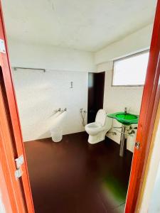 a bathroom with a toilet and a green table at Oval Retreat in Cochin