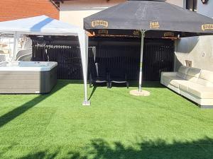 an umbrella on a lawn with a couch and a table at Apartman Ogulin "Klek Escape" in Sveti Petar