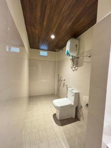 a bathroom with a toilet with a wooden ceiling at The Hillshade villa in Borpāni