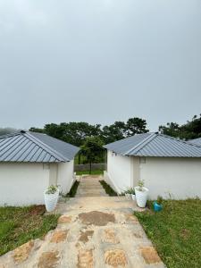 two white buildings with black roofs and some plants at The Hillshade villa in Borpāni +12 photos