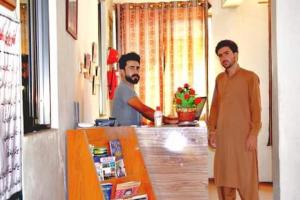 two men standing in front of a counter at Yasin Holiday Hotel in Gilgit