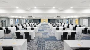 a large room with white tables and black chairs at voco St. Johns Solihull by IHG in Solihull +79 photos
