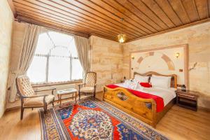 a bedroom with a bed and two chairs and a window at Akuzun Stone Hotel in Ürgüp