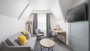 a living room with a couch and a table and a desk at voco St. Johns Solihull by IHG in Solihull