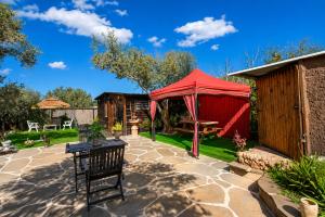 a patio with a red tent in a yard at השקט של כליל - בקתה קסומה בטבע עם בריכה פרטית in Clil