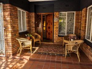 a porch with wicker chairs and a wooden door at Tree Aloe Guest House in Mokopane