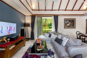 a living room with a couch and a tv at Katamanda B2 Tropical Pool Villa Kata Beach in Kata Beach
