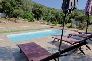 a patio with two chairs and an umbrella and a pool at Villa A Liccia - Piscine & Vue Maquis - 8 Pers in Figari