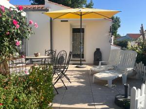 a patio with a table and chairs and an umbrella at Le temps d une escapade vendéenne in Saint-Gervais