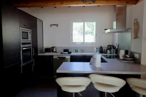 a kitchen with a counter with four stools in it at Villa A Liccia - Piscine & Vue Maquis - 8 Pers in Figari