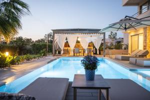 a large swimming pool with a table in front of a house at Ocean Private Villas - Pefkochori Halkidiki in Pefkochori