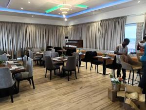a restaurant with tables and chairs and a man standing in a room at Movela Hotels in Warri