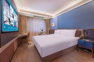 a bedroom with a large white bed and a tv at Orange Hotel Hangzhou Joy City in Hangzhou +34 photos
