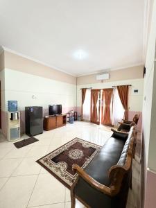 a large living room with a couch and a tv at Adiputra Guesthouse Tata Bumi by HomiQ in Yogyakarta