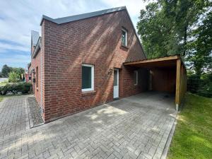 a red brick building with a garage and a driveway at Loft Hesel, 35232 in Hesel