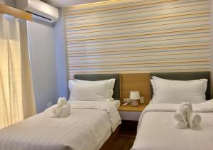 two beds with stuffed animals on them in a bedroom at ECL Travellers Inn in Nabas +3 photos