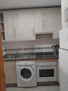 a kitchen with a washing machine and white cabinets at EDIFICIO SANTA GEMA 2k in La Cala de Mijas