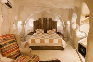 a bedroom with a large bed and a chair at Cappadocia Cave Suites in Göreme