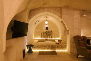 a living room with a tv and a wall at Cappadocia Cave Suites in Göreme +122 photos