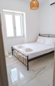 a bed in a white room with a window at The Rock Seaside House - Etheras Properties in Kythira