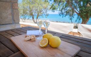 a wooden table with two glasses of wine and lemons at The Rock Seaside House - Etheras Properties in Kythira