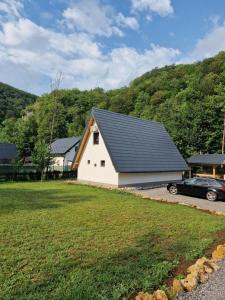 a white house with a black roof and a car at River Zen House in Šipovo