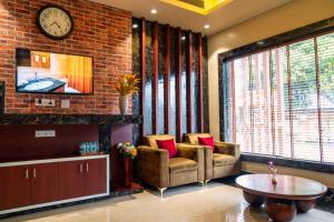 a living room with two chairs and a clock on a brick wall at Odissey Suites in Bhubaneshwar