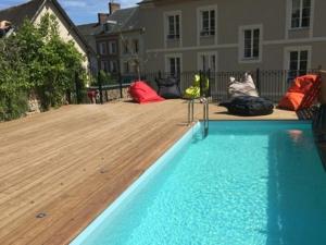 a swimming pool in a yard with a wooden deck at L'Escale de Broglie in Broglie