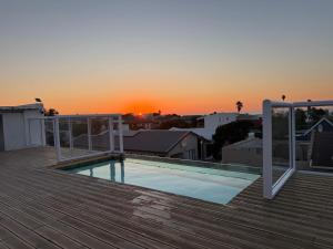 a pool on the roof of a house with the sunset at Skypool Guesthouse in Cape Town