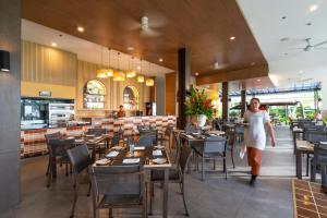 a woman walking through a restaurant with tables and chairs at Kantary Beach Hotel Villas & Suites in Khao Lak