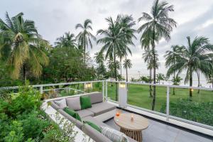 a balcony with a couch and a table and palm trees at Kantary Beach Hotel Villas & Suites in Khao Lak