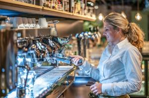 a woman standing behind a counter in a coffee shop at Summio Vakantiepark Schaijk in Schayk