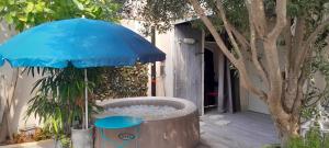 a hot tub with a blue umbrella next to a tree at Chambre d'hôte chez Nicole et Pierre in Eyragues
