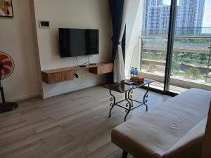 a living room with a flat screen tv and a table at Marina vinhomes in Long Bình