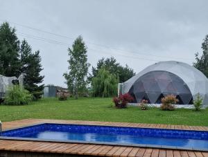 a large dome tent in a yard with a swimming pool at Rojus dviems in Žaugėdai