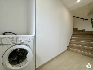 a washing machine in a laundry room with stairs at Le Creux Percé in Pasques