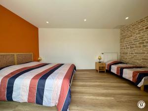 a bedroom with two beds and a brick wall at Le Creux Percé in Pasques