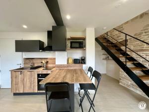 a kitchen with a wooden table and black chairs at Le Creux Percé in Pasques
