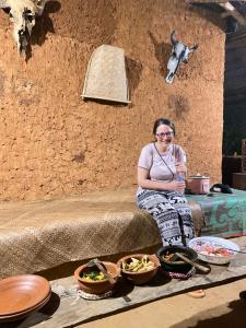 a woman sitting on a couch with bowls of food at Thanamal-villa in Tanamalwila