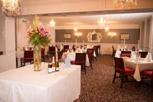 uma sala de banquetes com mesas brancas, cadeiras e flores em Devon Inn Hotel em Templeglantine