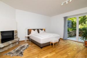 a white bedroom with a bed and a fireplace at Kaiser's Hof in Strass