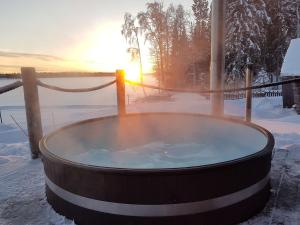 a hot tub in the snow with the sunset in the background at Villa Moinalahti in Sirkkakoski