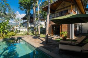 a house with a swimming pool and an umbrella at Plataran Borobudur in Borobudur