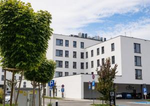 a white building with trees in front of it at Arche Hotel Piła in Piła