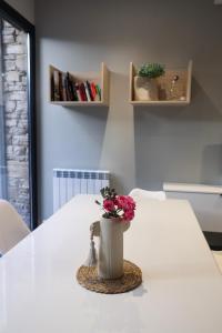 a white table with a vase with flowers on it at Cal Teca Rural in Sant Antolí i Vilanova