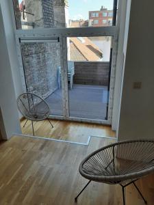 a balcony with two chairs and a large window at apartment Amsterdamstr 1st fl in Ostend +3 photos