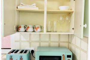 a kitchen with a toaster and cups on a shelf at Cozy Grays Apartment in Grays Thurrock
